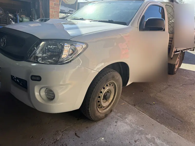 White Toyota Hilux ute after front-end repair, front left side with new headlight and bumper