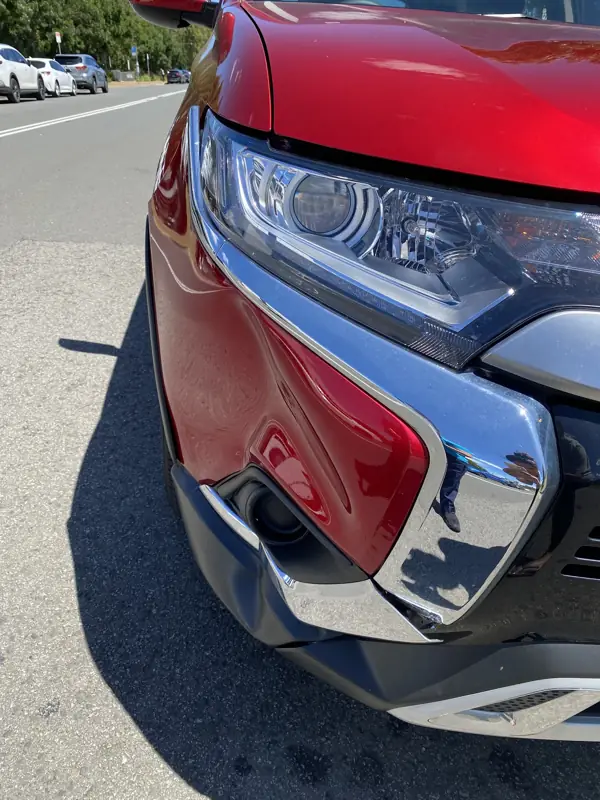 Mitsubishi Outlander with a damaged front bumper and headlight surround